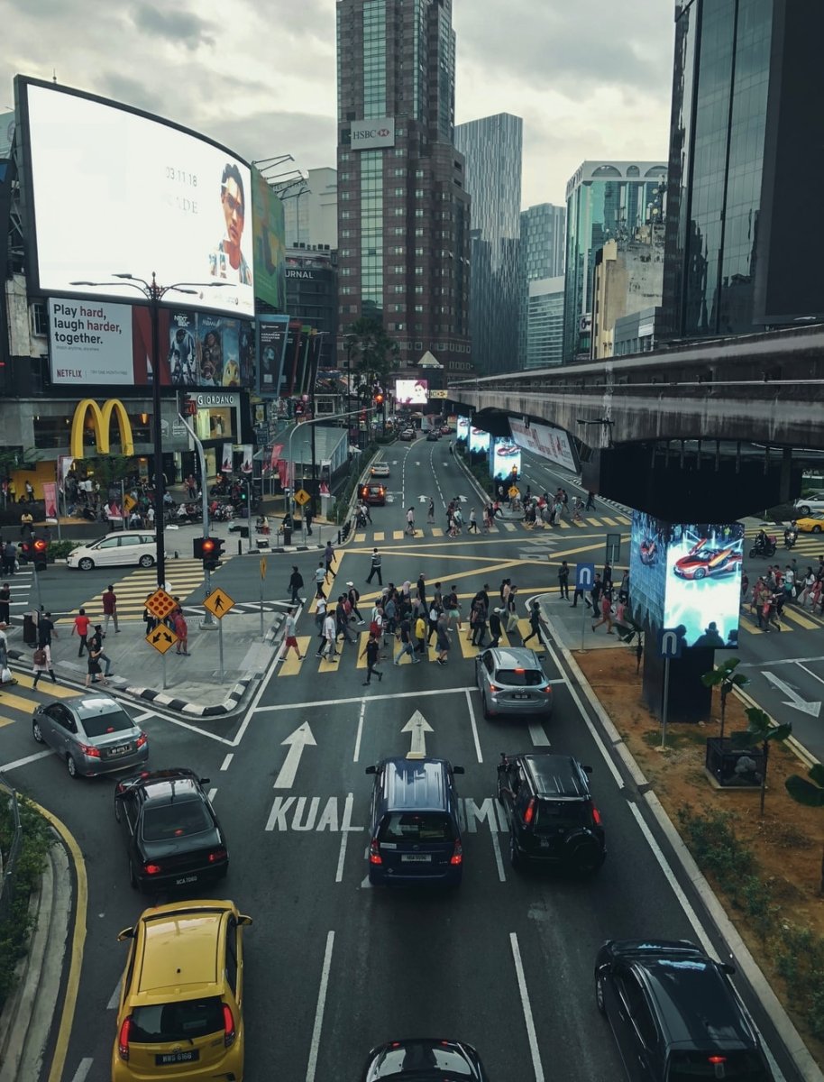 Paint By Numbers | Kuala Lumpur - People Walking On Pathway Near Buildings And Different Vehicles On Road Under White And Gray Sky During Daytime - Custom Paint By Numbers